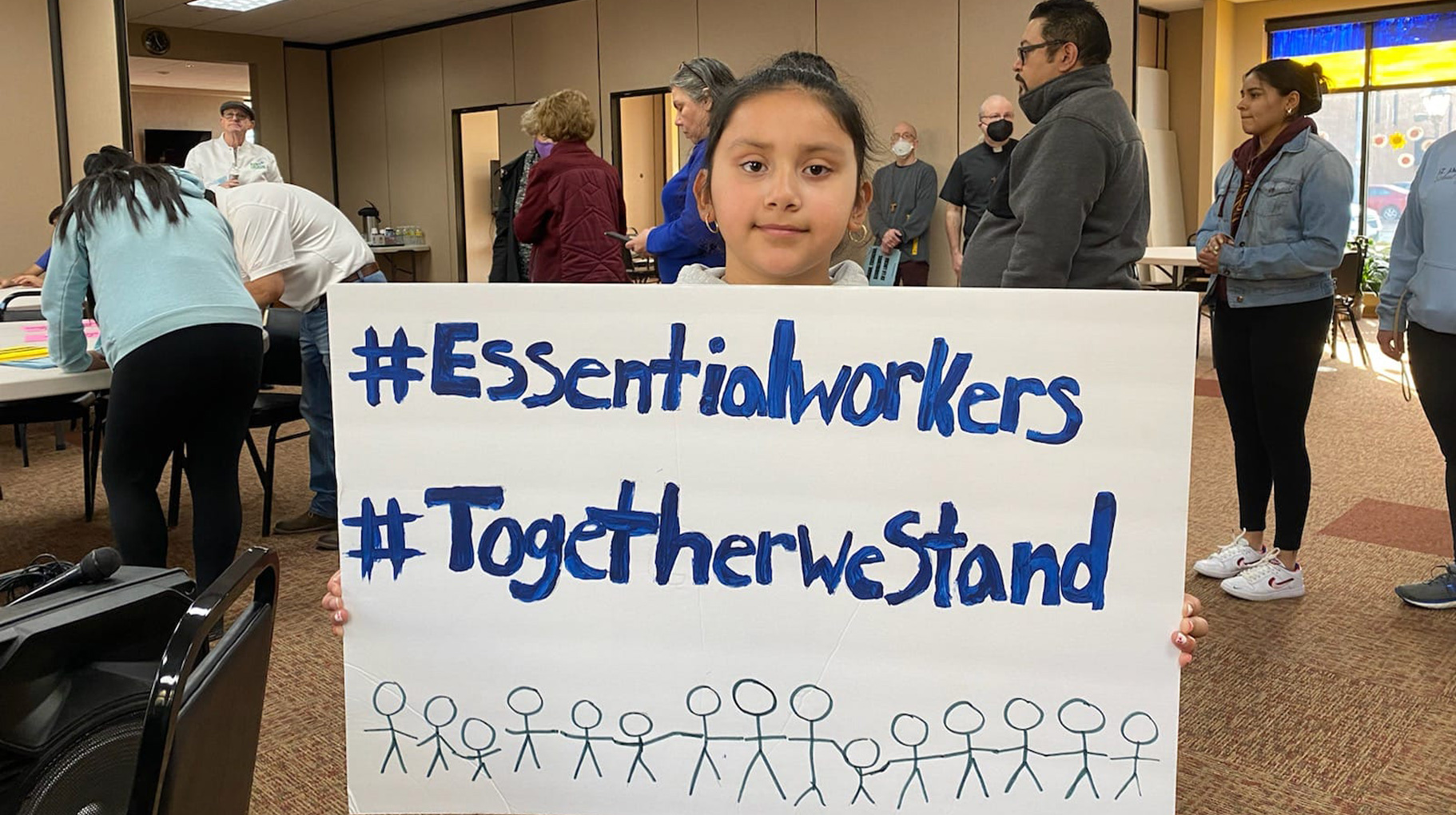 A child holding a sign supporting essential workers